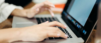 Hands typing on a laptop keyboard